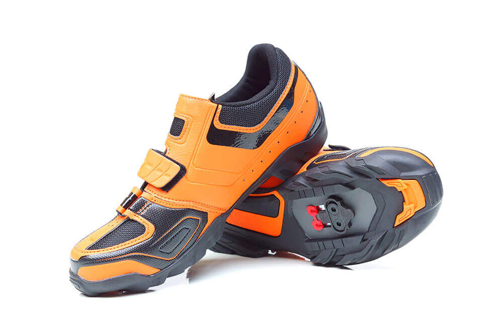 A pair of orange cycling shoes with a white background
