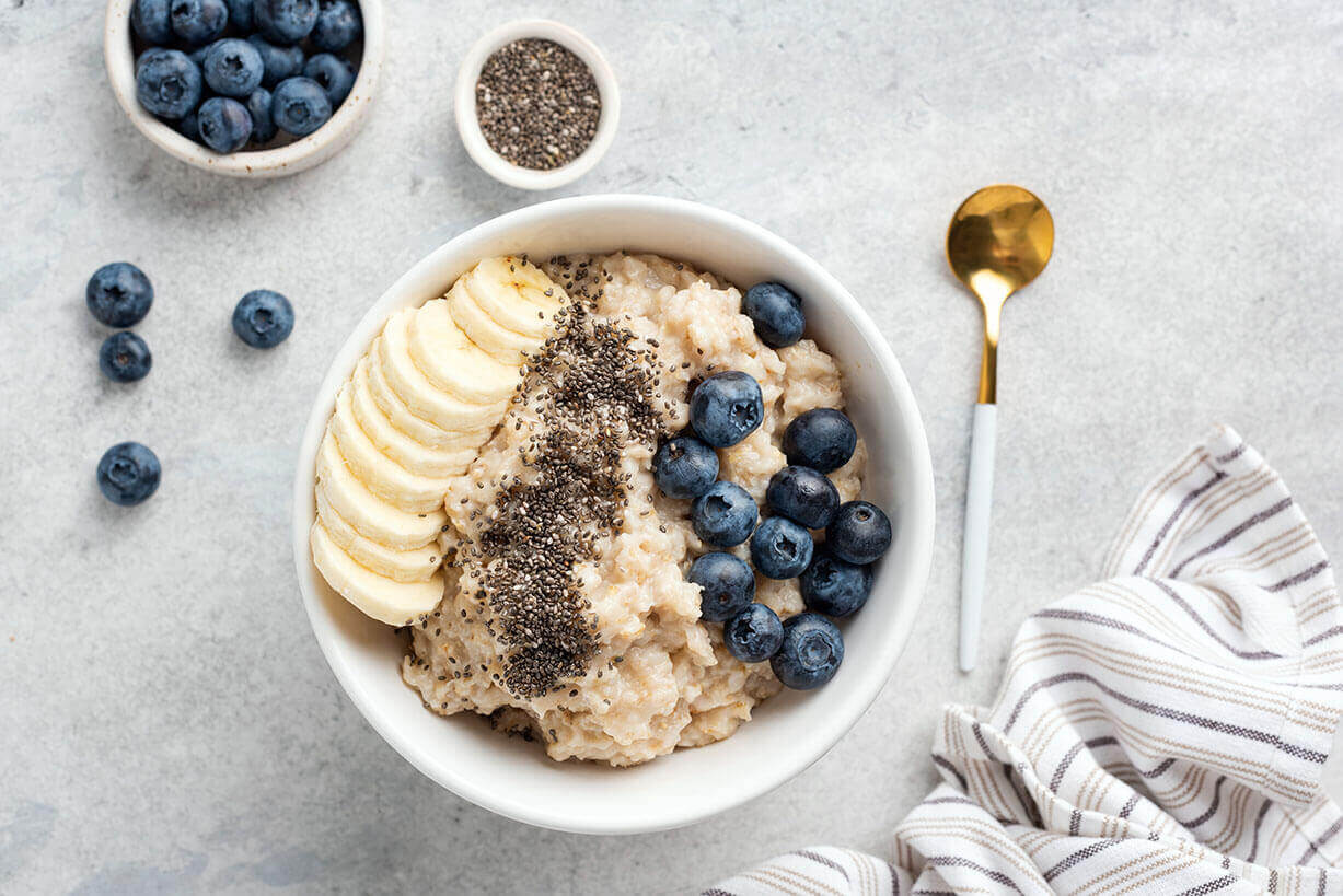 A bowl of oatmeal with bananas and blueberries