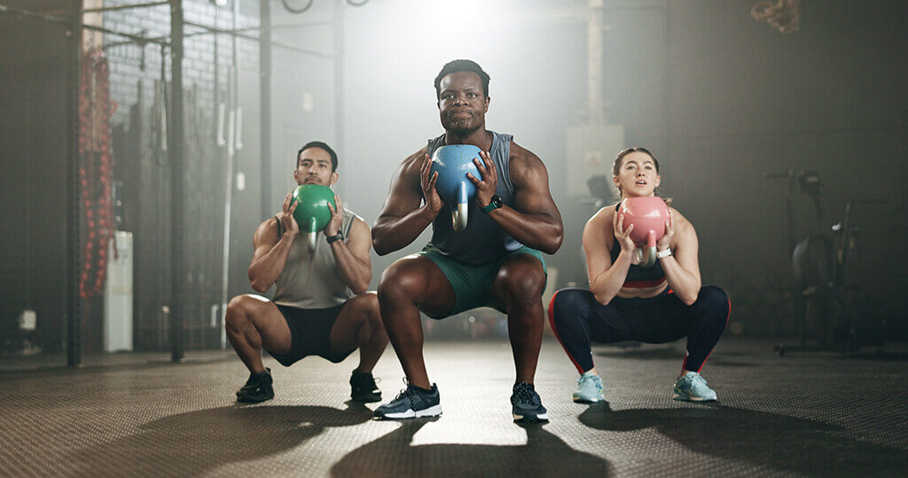 Three people doing squats as part of their cross training exercises