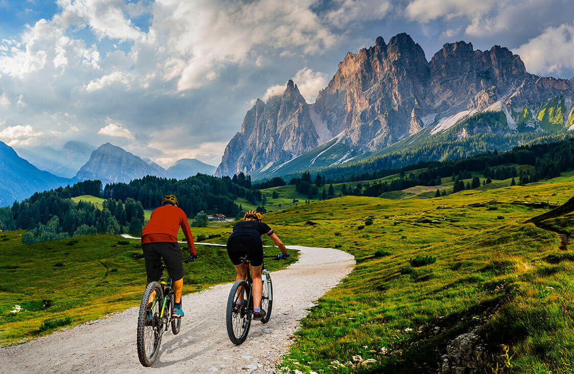 Two cyclists riding on a gravel trail in the mountains