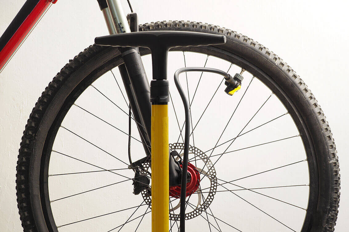 A tire pump with a pressure gauge pumping up a bicycle tire