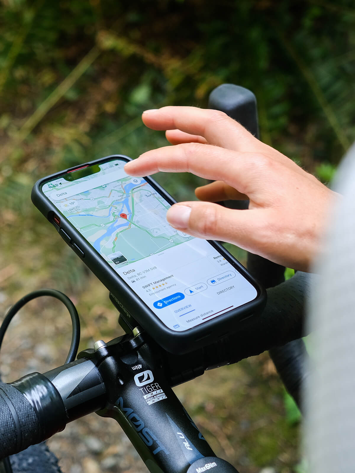 Cyclist checking they trail map on their phone. They are using a StrideCharge Charge Case and Bike Mount