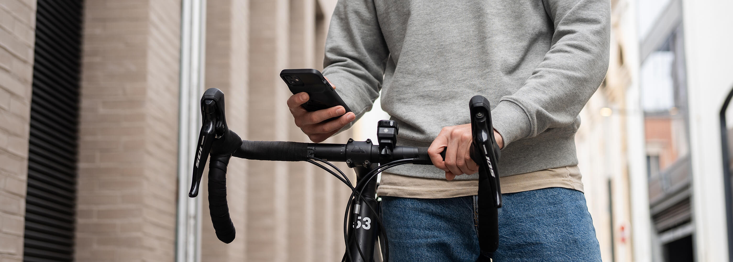 A cyclist walking beside his bike and using his phone with the Stride Charge Case on his phone