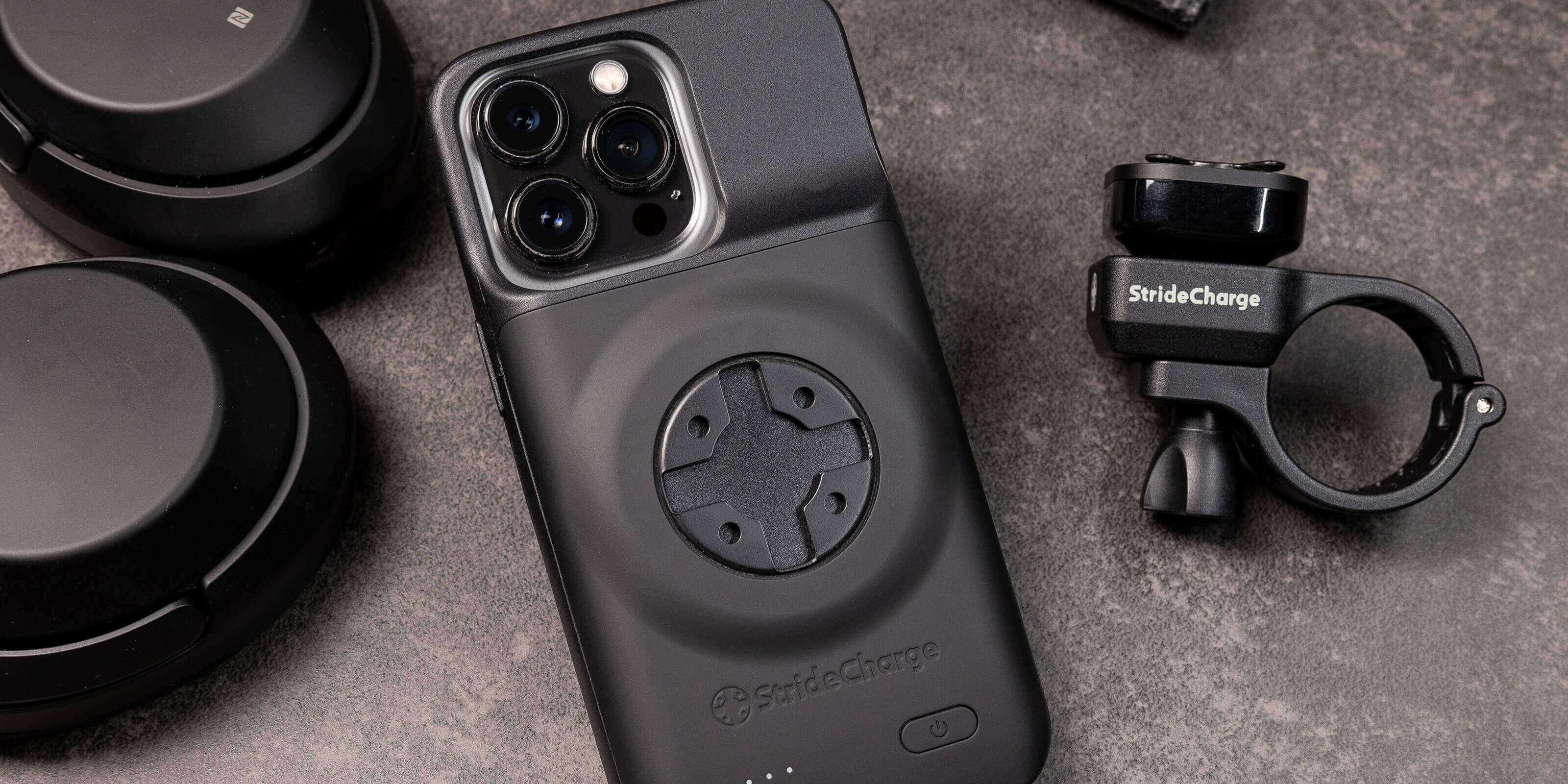 StrideCharge Case and Mount on a dark table with head phones and a book